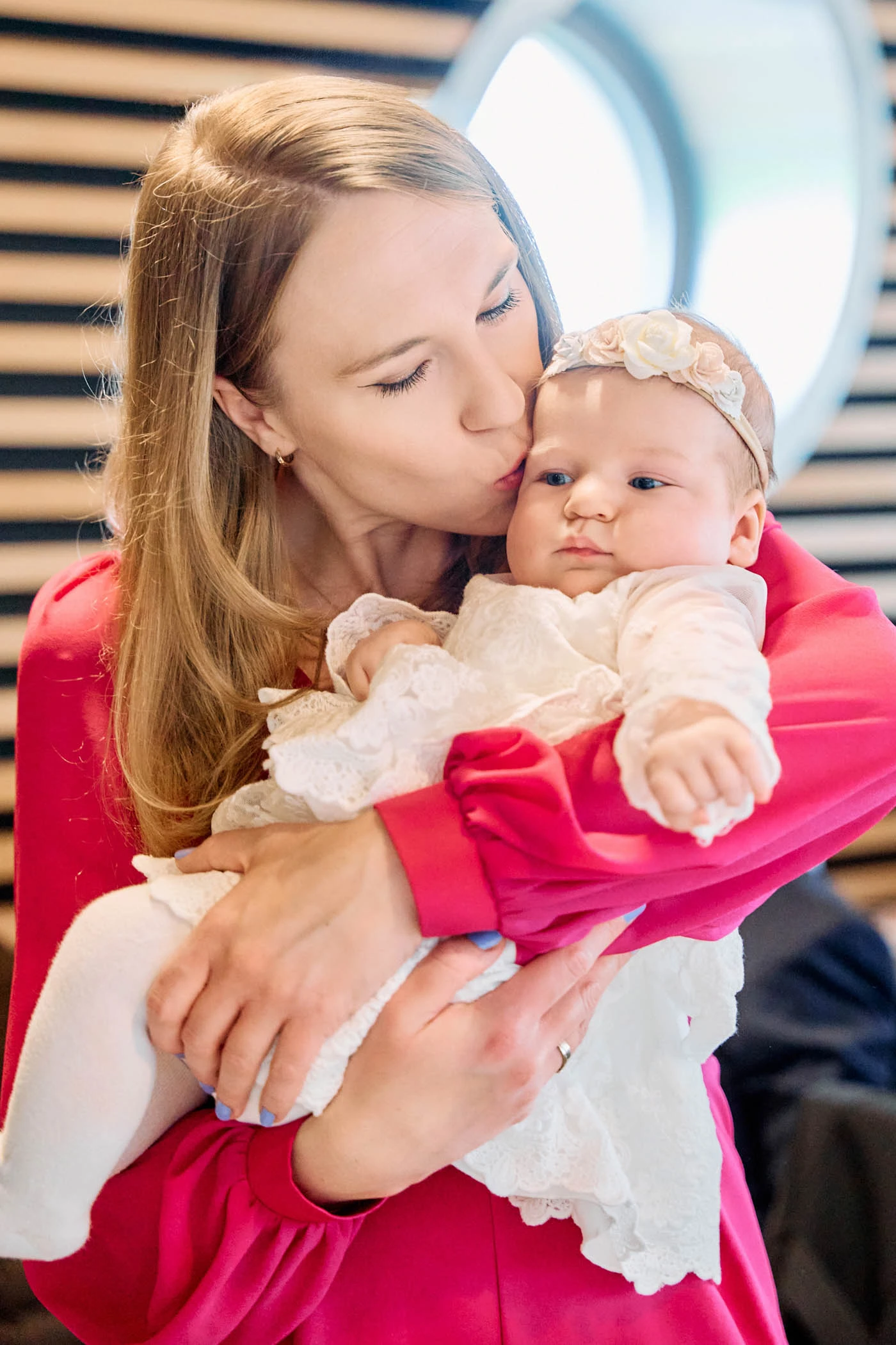 kbart krzysztof bartnik mama w rozowej bluzce caluje niemowle w bialej sukience do chrztu